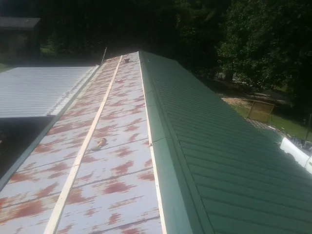 Old rusted panels beside newly installed green metal roofing — Wind Damage Roof Repair by Roofing Brothers in Bellaire