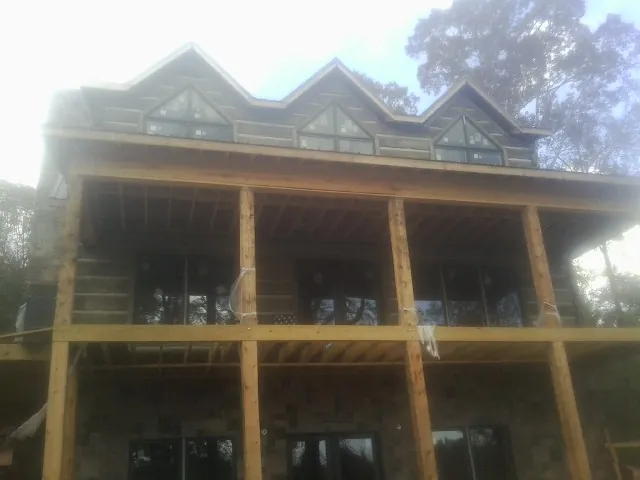 Dormers and porch framing on a large log home under construction — Roof Coating work by our crew in Bellaire