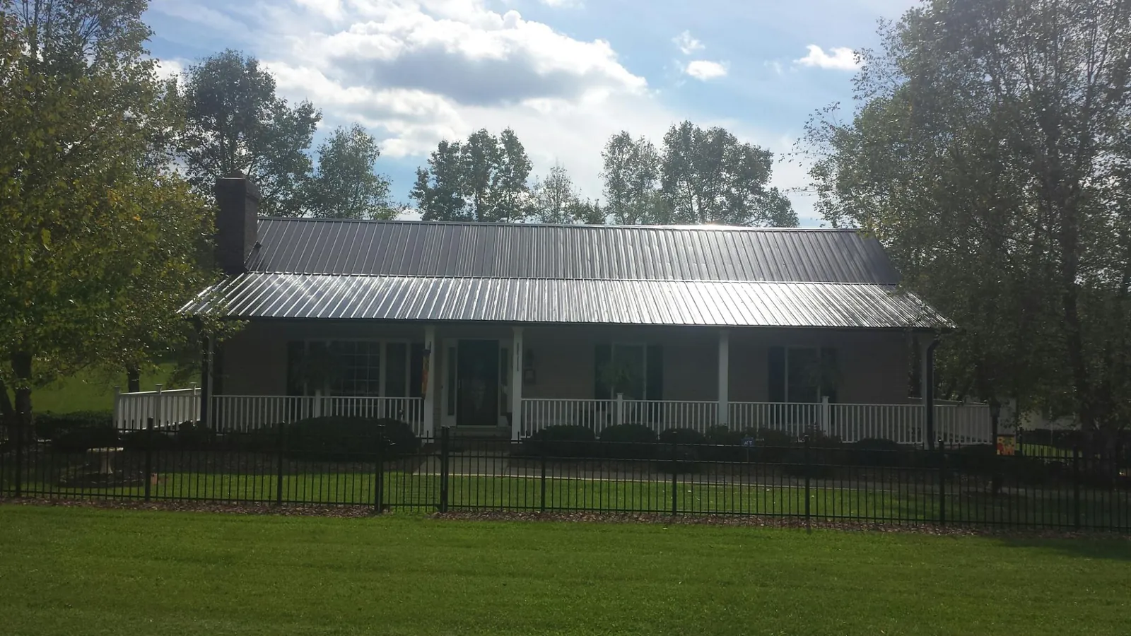 Gray metal roof on a brick ranch with a full width front porch — Gutter Guard Installation work by our crew in Bellaire